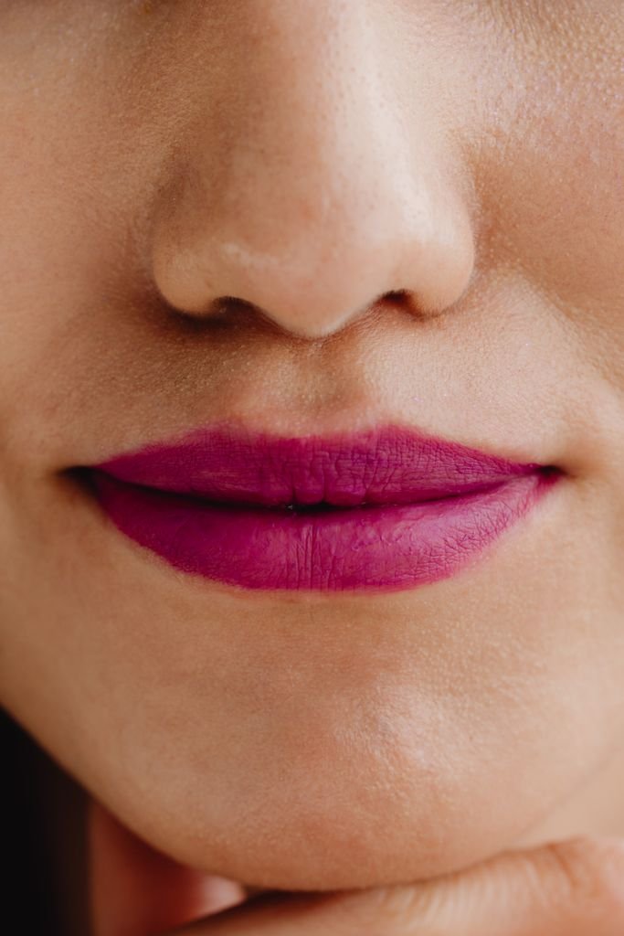 Close-up of dewy skin with a deep berry lipstick
