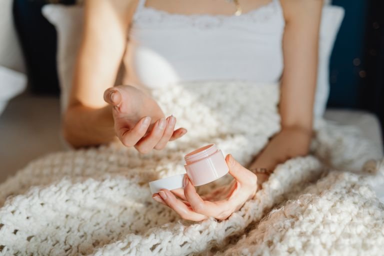 Woman applying rich moisturizer as part of a winter skincare routine for dry skin