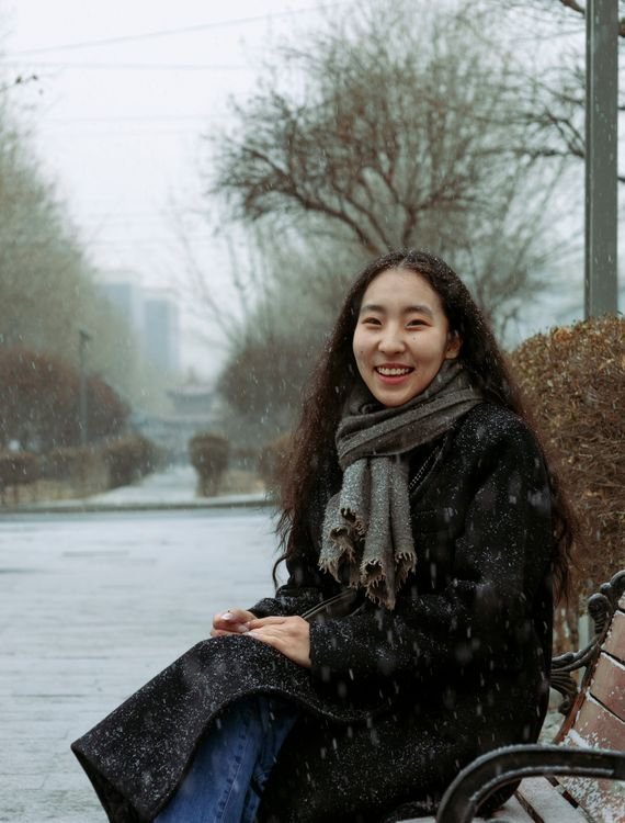 Korean winter fashion with oversized scarf and wool coat in falling snow